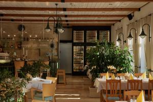 a restaurant with white tables and chairs and plants at Öreg Halász Fogadó in Tát