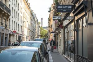 a man walking down a street with parked cars at Sweet Inn - Rue Duret in Paris
