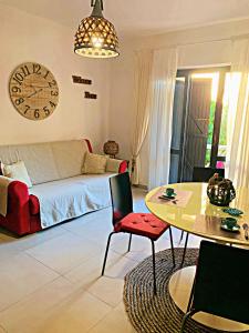 a living room with a couch and a table and a clock at IL MIRTO - Accogliente bilocale a Capo Testa - IUN R5566 in Santa Teresa Gallura