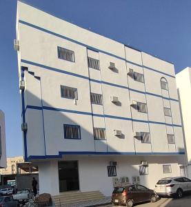 a large white building with blue stripes on it at DAR MOHAMMED HOTEL دار محمد فندق in Sīdī Ḩamzah