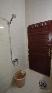 a bathroom with a shower and a door with a bucket at DAR MOHAMMED HOTEL دار محمد فندق in Sīdī Ḩamzah