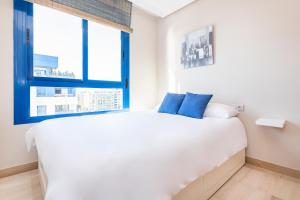 a white bed in a room with a window at BHost - Pacífico in Málaga