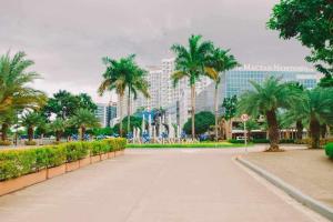 a street with palm trees and a large building at Mactan Cebu Beach Condo in Punta Engaño