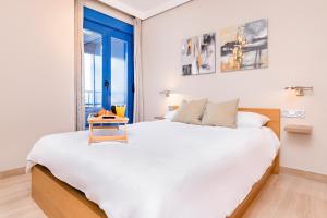 um quarto com uma grande cama branca e uma porta azul em BHost - Pacífico em Málaga