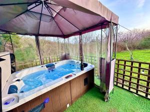 a hot tub with an umbrella in a yard at THREE BEDROOM Rural, relaxing and peaceful,DOGS welcome! in Abergavenny