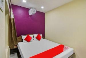 um quarto com uma cama vermelha e branca com uma parede roxa em HOTEL AIRPORT HEAVEN em kolkata