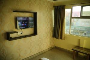 um quarto com uma televisão de ecrã plano na parede em HOTEL AIRPORT HEAVEN em kolkata