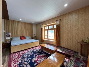 a bedroom with a bed and a window and a rug at SNOWFLAKE Homestay in Gondla