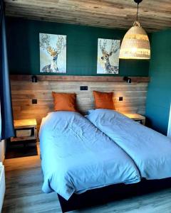 - une chambre dotée d'un lit avec des draps bleus et des peintures de cerfs dans l'établissement Renée Cense, à Houffalize