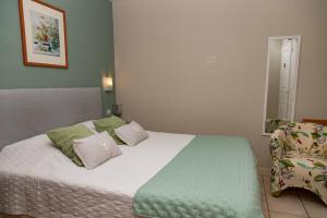 Chambres d'Ault في أولت: غرفة نوم بسرير كبير ومخدات خضراء وبيضاء