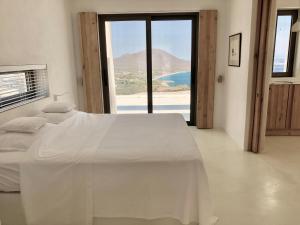 een slaapkamer met een wit bed en uitzicht op de oceaan bij Mr. Bliss in Avlemonas
