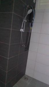 a shower in a bathroom with black and white tiles at Horizon Suites Ezhome in Sepang