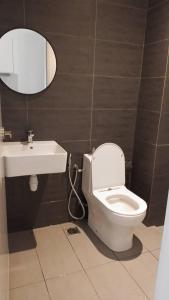 a bathroom with a toilet and a sink and a mirror at Horizon Suites Ezhome in Sepang