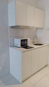 a white kitchen with a microwave and a sink at Horizon Suites Ezhome in Sepang