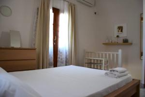 a bedroom with a white bed and a window at Absolute peace north villa by the volcanic slopes in Imerovigli