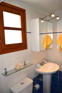 a bathroom with a sink and a toilet and a mirror at Absolute peace north villa by the volcanic slopes in Imerovigli