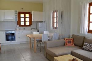 a kitchen and living room with a couch and a table at Absolute peace north villa by the volcanic slopes in Imerovigli +24 photos