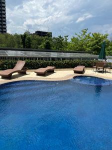 a large swimming pool with chairs and umbrellas at Confort Suite autônoma Quality Rio Centro in Rio de Janeiro