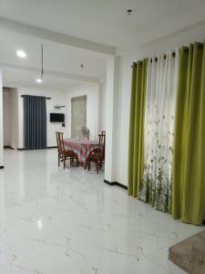 a dining room with a table and green curtains at White's vila in Matara