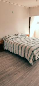 a bed with a striped comforter in a bedroom at Acogedor departamento 2 Habitaciones y 2 baños Santiago de Chile in Santiago