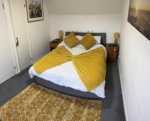 a bedroom with a bed with a yellow blanket at No.46, comfortable 2 bedroom property in Rothes