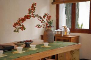 una mesa con un jarrón con flores rojas. en 松玉枫民宿, en Guiyang