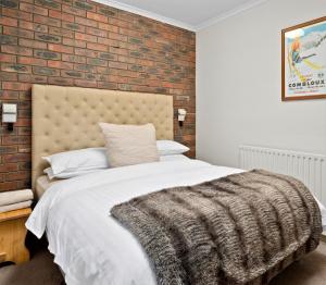 Un dormitorio con una pared de ladrillo y una cama en Hotel Pension Grimus, en Mount Buller