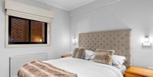 a bedroom with a white bed and a window at Hotel Pension Grimus in Mount Buller
