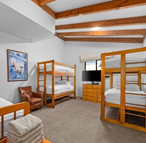 a room with three bunk beds and a couch at Hotel Pension Grimus in Mount Buller