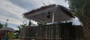 una cabaña blanca con techo de paja sobre una valla en นรดีฮิวล์ รีสอร์ต เขาแผงม้า วังน้ำเขียว, en Ban Sap Bon
