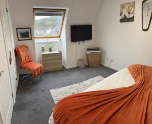 a bedroom with a bed and a tv and a chair at No.46, comfortable 2 bedroom property in Rothes