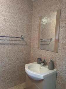 ein Badezimmer mit einem weißen Waschbecken und einem Spiegel in der Unterkunft Colț de rai - camera de inchiriat in Reşiţa