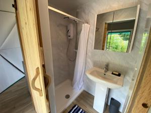 a bathroom with a sink and a shower with a mirror at Benllech Glamping in Benllech