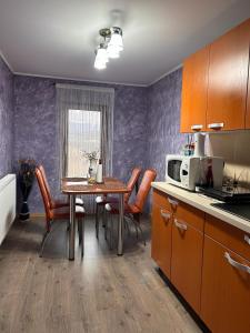 a kitchen with a table with chairs and a microwave at Colț de rai - camera de inchiriat in Reşiţa