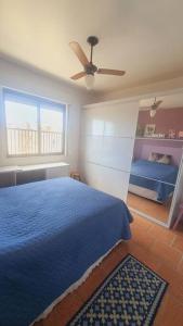 Schlafzimmer mit einem blauen Bett und einem Deckenventilator in der Unterkunft *Apê charmoso com vista do mar in Capão da Canoa