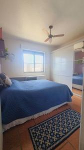 Schlafzimmer mit einem blauen Bett und einem Deckenventilator in der Unterkunft *Apê charmoso com vista do mar in Capão da Canoa
