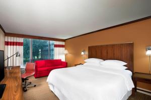 a hotel room with a bed and a red chair at Four Points by Sheraton Kansas City Airport in Kansas City