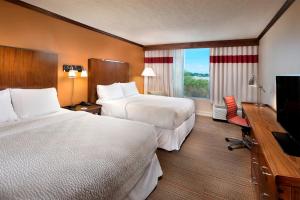 a hotel room with two beds and a flat screen tv at Four Points by Sheraton Kansas City Airport in Kansas City