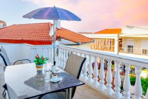 a balcony with a table and an umbrella at Maria Rooms in Polychrono