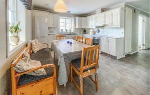 cocina con mesa, sillas y armarios blancos en Cozy Home In Gislaved With Wifi, en Hornbetan