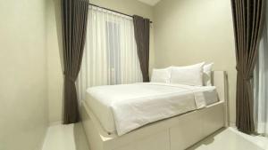 a white bed in a room with a window at Ghani Villa in Tlekung