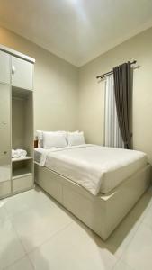 ein weißes Schlafzimmer mit einem Bett und einem Spiegel in der Unterkunft Ghani Villa in Tlekung