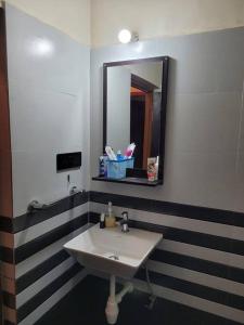 La salle de bains est pourvue d'un lavabo et d'un miroir. dans l'établissement Comfortable 1BHK Resort Aptmt with Pool at Candolim for 4 ppl, à Goa