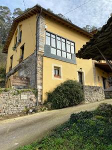 a yellow house with a stone wall next to a road at LOS CARBAYINOS in Villaviciosa