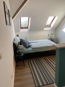 1 dormitorio con 1 cama con 2 ventanas y alfombra en Kleines Apartment in Mönchengladbach-Neuwerk, en Mönchengladbach