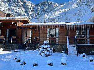a snow covered cabin with a snow covered mountain at Panorama Cottages in Stepantsminda