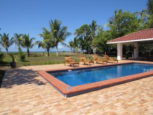a swimming pool with benches next to a resort at Casa Pacifico Panama in Las Lajas