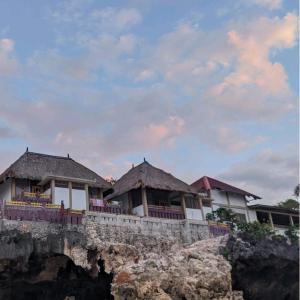 a row of houses on a cliff near the ocean at Villa Redemptorist in Weetebula