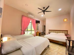 a bedroom with two beds and a ceiling fan at Besut Guesthouse in Kuala Besut