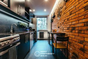 a kitchen with a brick wall next to a table at Happy Time - Happy Apartamenty Mielec in Mielec